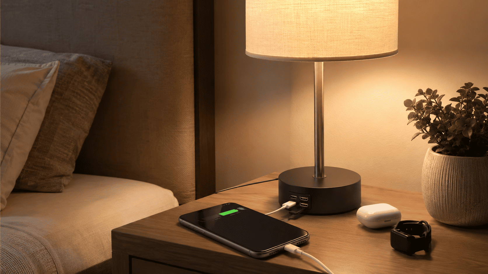 Lámpara de mesita de noche con puertos USB cargando un móvil y accesorios